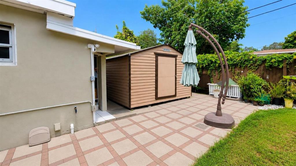 A tan storage shed sits on a paved patio next to a house exterior — 2311 N 58TH AVENUE, HOLLYWOOD, FL
