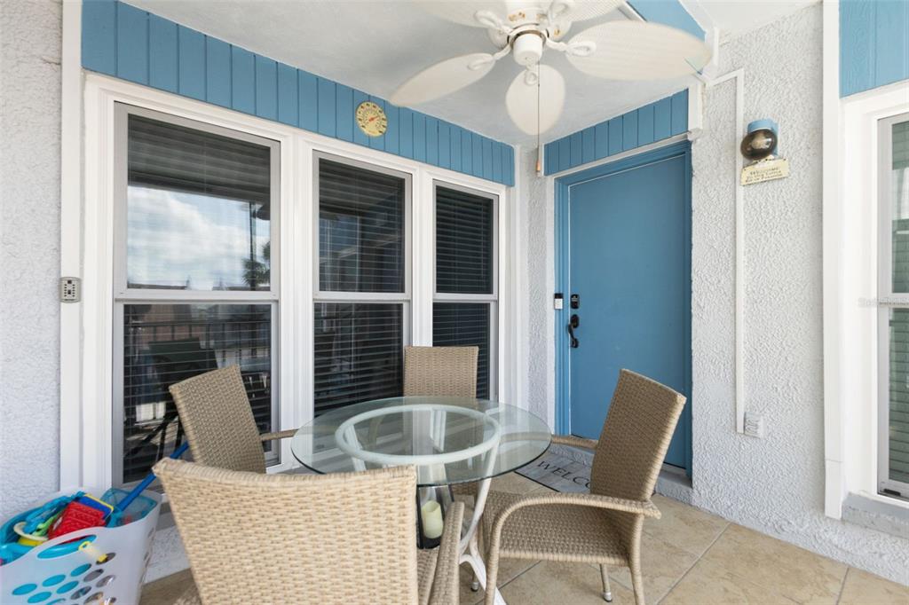 A patio features a glass-topped table with four wicker chairs, a ceiling fan, and blue accents — 337 REX PLACE UNIT G, MADEIRA BEACH, FL