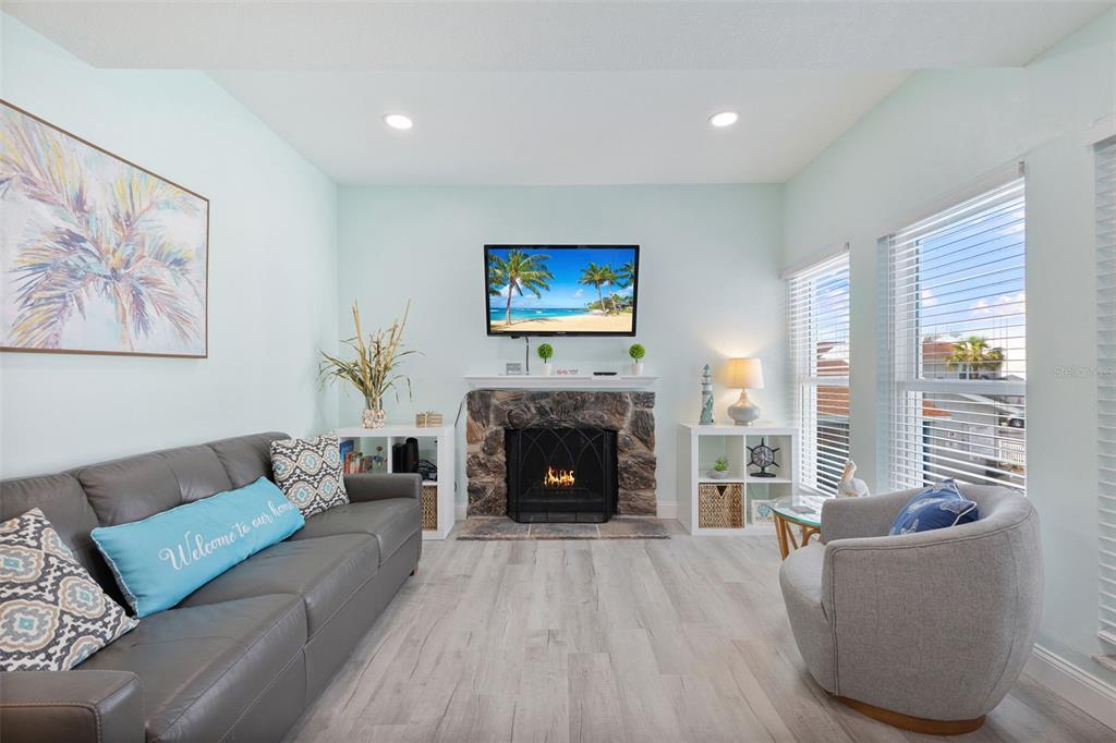 A living room features a stone fireplace, a gray sofa, and a swivel armchair — 337 REX PLACE UNIT G, MADEIRA BEACH, FL