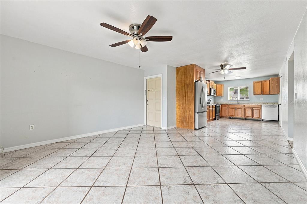 An open-concept room features light gray walls, tiled floors, a ceiling fan, and a kitchen — 1000 LAKE OF THE WOODS BOULEVARD UNIT 105E, FERN PARK, FL