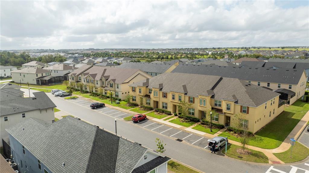 An aerial view shows a row of tan townhomes with gray roofs and parking spaces — 2194 FLEMING MIST PLACE, KISSIMMEE, FL