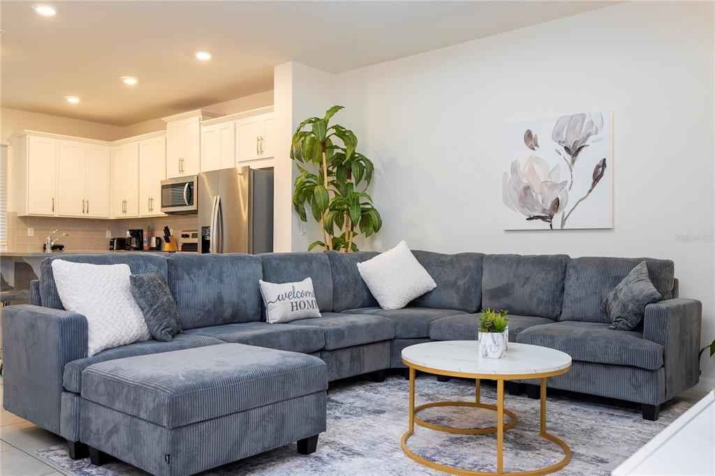 A living room features a large grey sectional sofa, a round coffee table, and a plant — 2194 FLEMING MIST PLACE, KISSIMMEE, FL