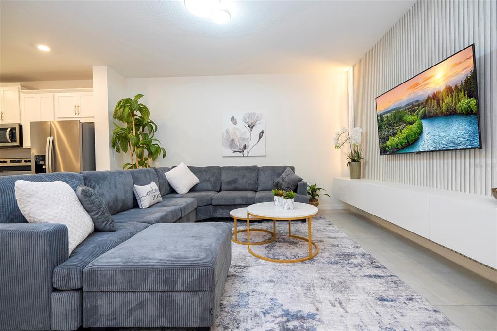 A living room features a grey sectional sofa, two round coffee tables, and a wall-mounted television — 2194 FLEMING MIST PLACE, KISSIMMEE, FL