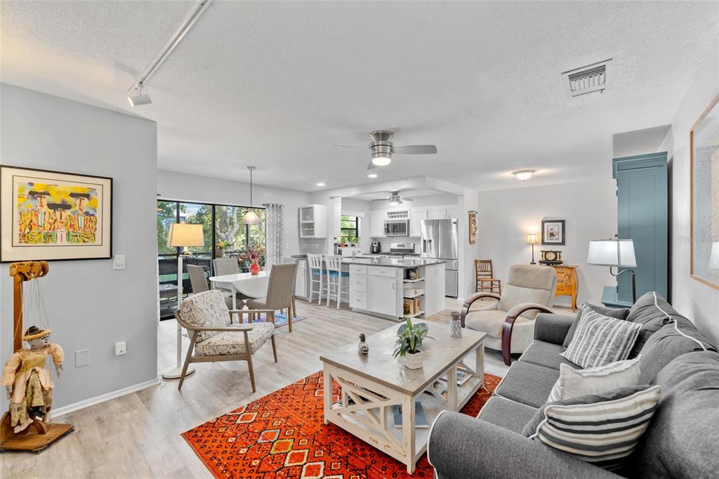 An open-concept living and dining area features light wood flooring, a kitchen island, and furniture — 5970 80TH STREET N UNIT 309, ST PETERSBURG, FL