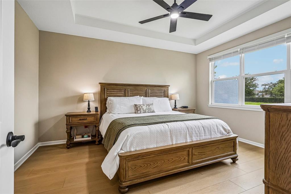 A bedroom features a wooden bed frame, light-colored walls, wood-look flooring, and a ceiling fan — 15873 GEM VIEW STREET, WINTER GARDEN, FL