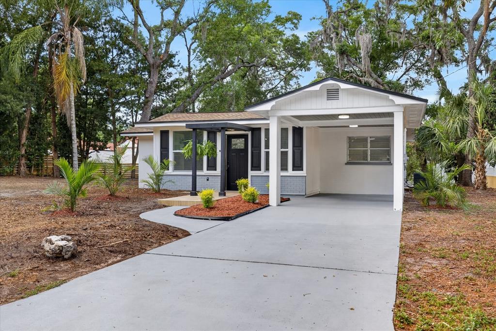 A single-story house with a white exterior, gray brick base, black shutters, and a carport — 7806 E 114TH AVENUE, TAMPA, FL