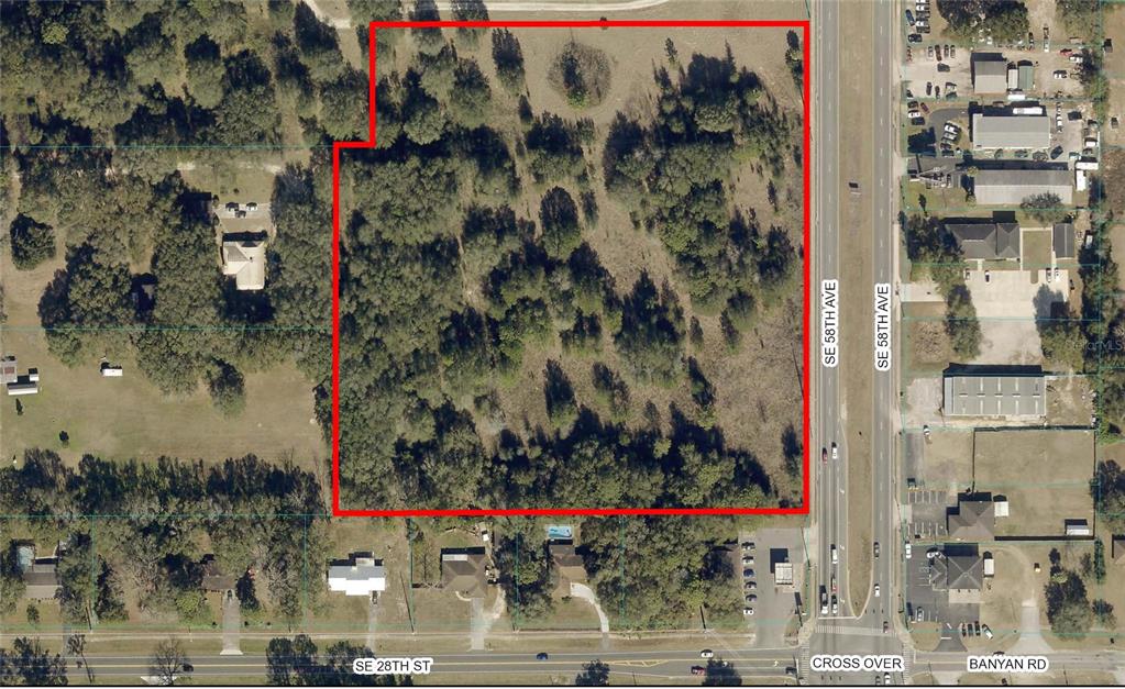 An aerial view shows a rectangular, tree-covered vacant lot outlined in red next to a road — 0 SE 58th AVENUE, OCALA, FL