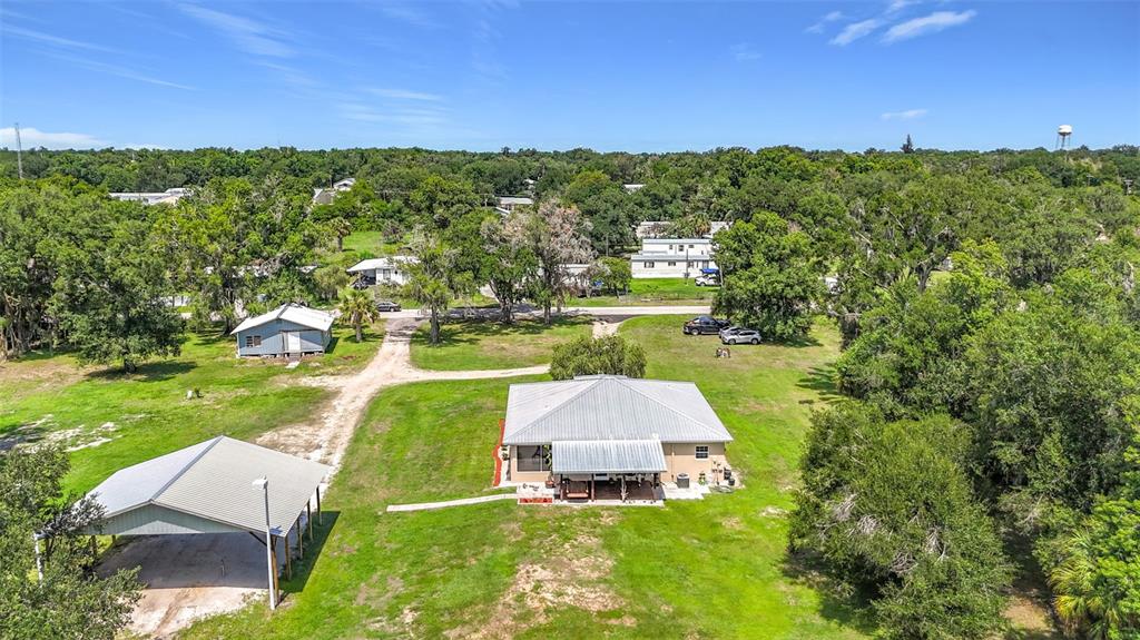 An aerial view shows a house with a metal roof, a detached carport, and surrounding trees — 273 GRIFFIN ROAD, WAUCHULA, FL