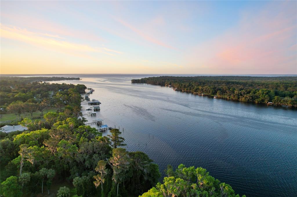 An aerial view shows a river flowing toward a large body of water at sunset — 356 DRAYTON ISLAND ROAD, GEORGETOWN, FL