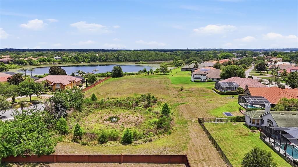 An aerial view shows a vacant residential lot situated between several houses and a lake — 11544 WILLOW GARDENS DRIVE, WINDERMERE, FL