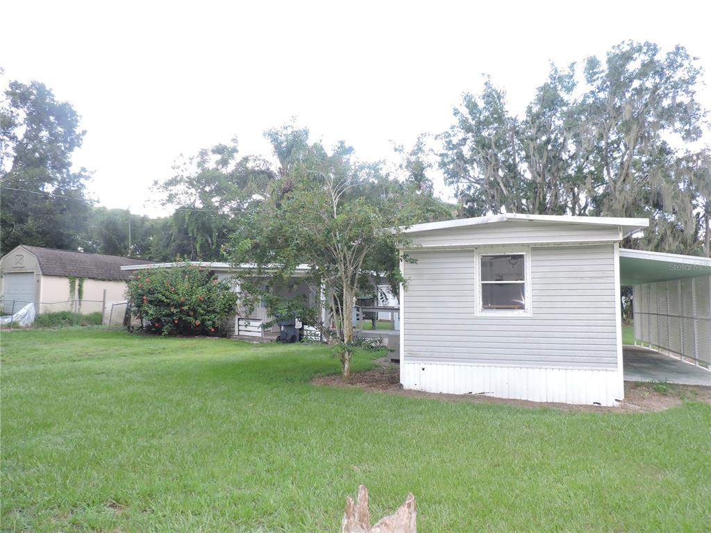 A light gray mobile home with a carport sits on a grassy lot with trees — 2530 SNAPPING TURTLE DRIVE, LAKE WALES, FL