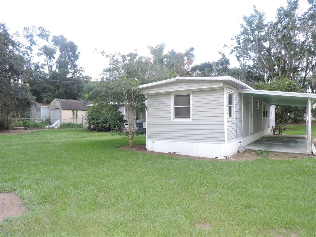 A light-colored mobile home with an attached carport sits on a grassy lot — 2530 SNAPPING TURTLE DRIVE, LAKE WALES, FL