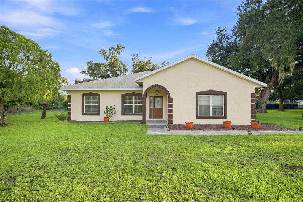 A single-story house with a beige stucco exterior, brown trim, and a front entryway arch — 1050 NE 165TH STREET, CITRA, FL