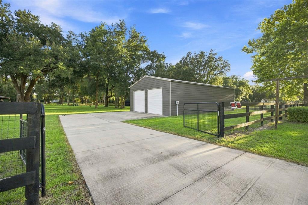 A detached metal garage with two white doors sits at the end of a concrete driveway — 1050 NE 165TH STREET, CITRA, FL
