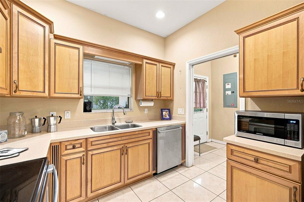 A kitchen with light wood cabinets, stainless steel appliances, a double sink, and tile flooring — 1050 NE 165TH STREET, CITRA, FL