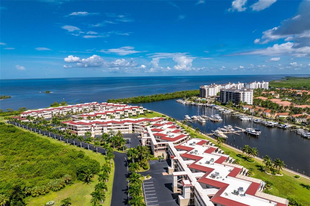 An aerial view shows a waterfront condominium complex with red roofs and a private marina — 3250 SOUTHSHORE DRIVE UNIT 55B, PUNTA GORDA, FL