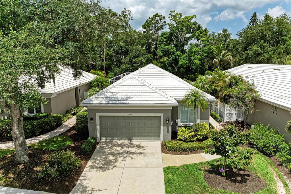 A paved patio features a covered grill, palm trees, and a screened-in pool enclosure — 5002 88TH STREET E, BRADENTON, FL