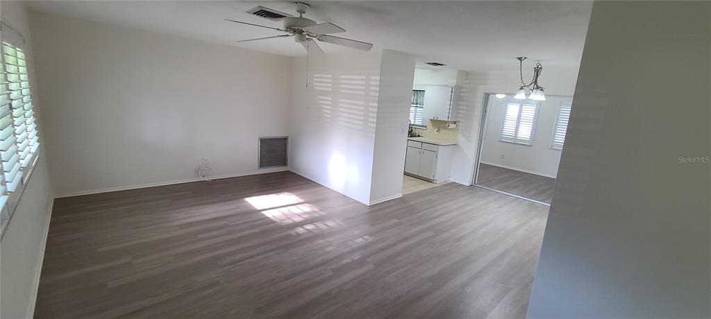 A living room with light wood-look flooring, a ceiling fan, and an adjacent kitchen area — 9901 111TH LANE, SEMINOLE, FL