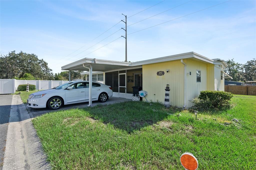 A yellow single-story house with a carport and a white car parked in front — 20 HAWAIIAN WAY, LEESBURG, FL