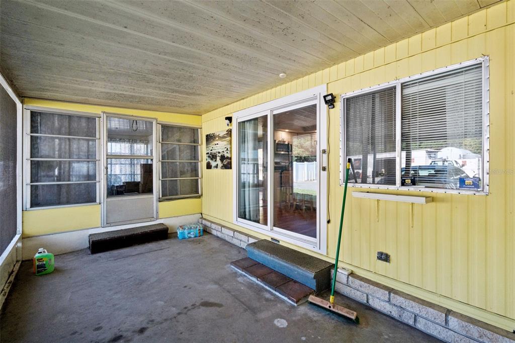 A covered patio with yellow siding, a sliding glass door, and a concrete floor — 20 HAWAIIAN WAY, LEESBURG, FL