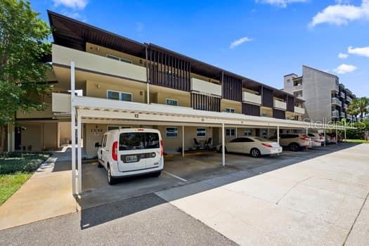 A white van is parked under a covered carport in front of a multi-story apartment building — 1239 S MARTIN LUTHER KING JR AVENUE UNIT 104, CLEARWATER, FL