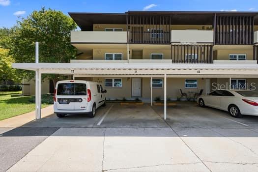 A multi-story apartment building exterior features a covered parking area with numbered spaces — 1239 S MARTIN LUTHER KING JR AVENUE UNIT 104, CLEARWATER, FL