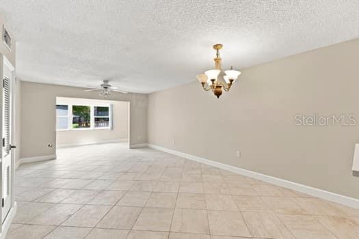An empty room with beige tile floors, a ceiling fan, and a traditional chandelier — 1239 S MARTIN LUTHER KING JR AVENUE UNIT 104, CLEARWATER, FL