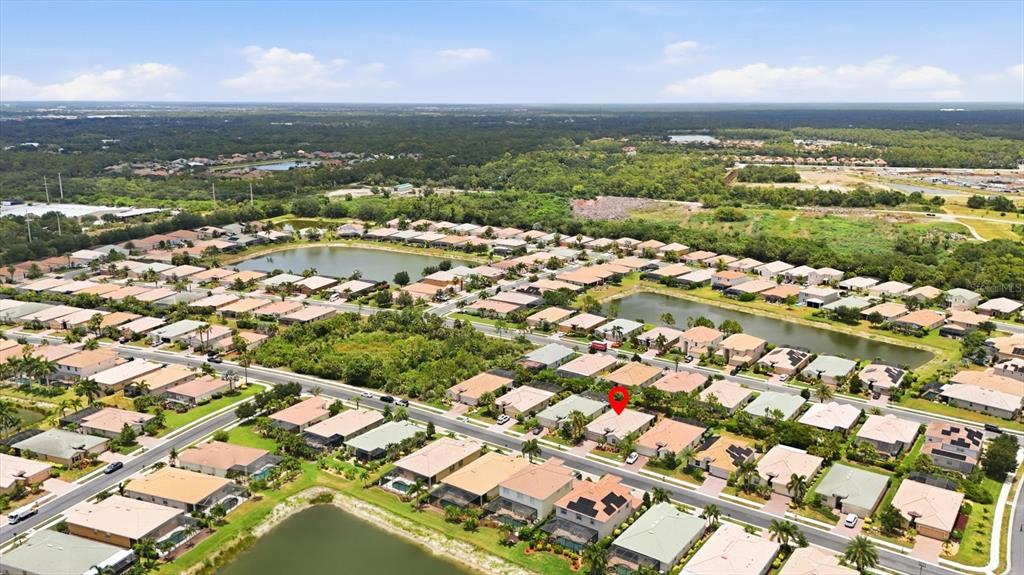 An aerial view shows a residential neighborhood with houses, ponds, and a red location marker — 11702 ANHINGA AVENUE, VENICE, FL