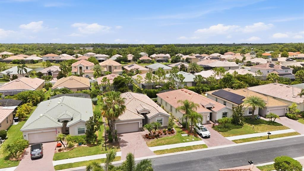 An aerial view shows a suburban neighborhood with single-family homes, paved driveways, and palm trees — 11702 ANHINGA AVENUE, VENICE, FL