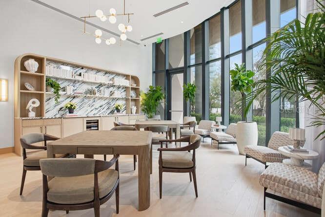 A modern lounge area features a wooden table, chairs, built-in shelving, and floor-to-ceiling windows — 3015 S YSABELLA AVENUE UNIT 2703, TAMPA, FL