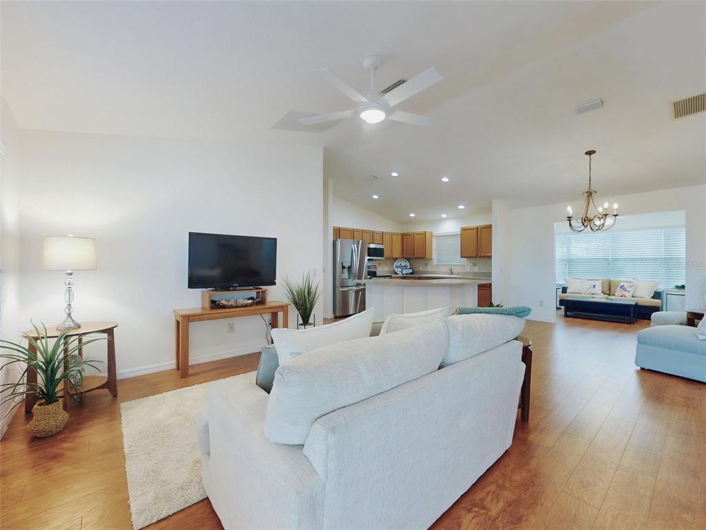 A living room features a front door, wood flooring, a ceiling fan, and a console table — 1521 HOLLYBERRY PLACE, THE VILLAGES, FL