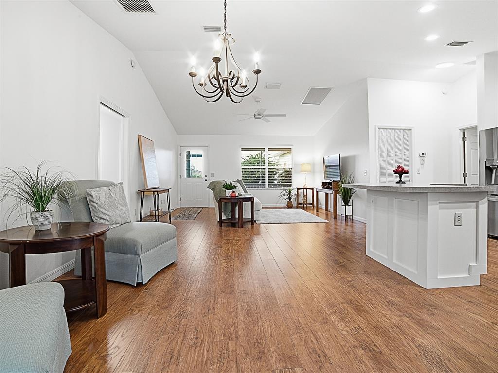 A kitchen features wood cabinets, stainless steel appliances, a white island, and wood-look flooring — 1521 HOLLYBERRY PLACE, THE VILLAGES, FL