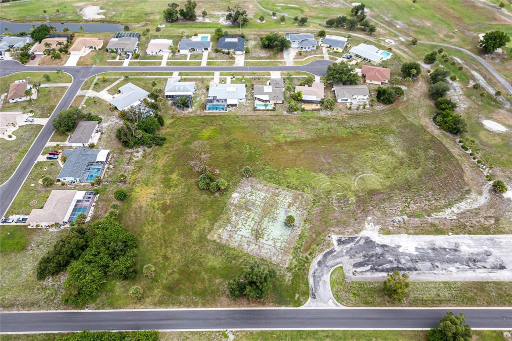 An aerial view shows a large, vacant grassy lot situated between residential streets and homes — 3 GOLFVIEW ROAD, ROTONDA WEST, FL