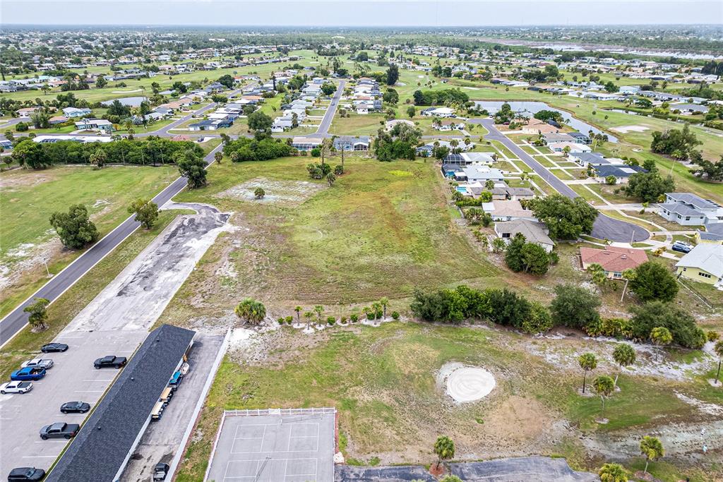 An aerial view shows a vacant lot adjacent to a parking lot and residential neighborhood — 3 GOLFVIEW ROAD, ROTONDA WEST, FL