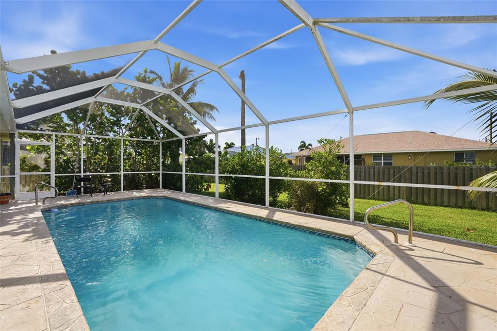 A rectangular swimming pool is enclosed by a white metal screen cage on a patio — 2408 SW 53RD STREET, CAPE CORAL, FL