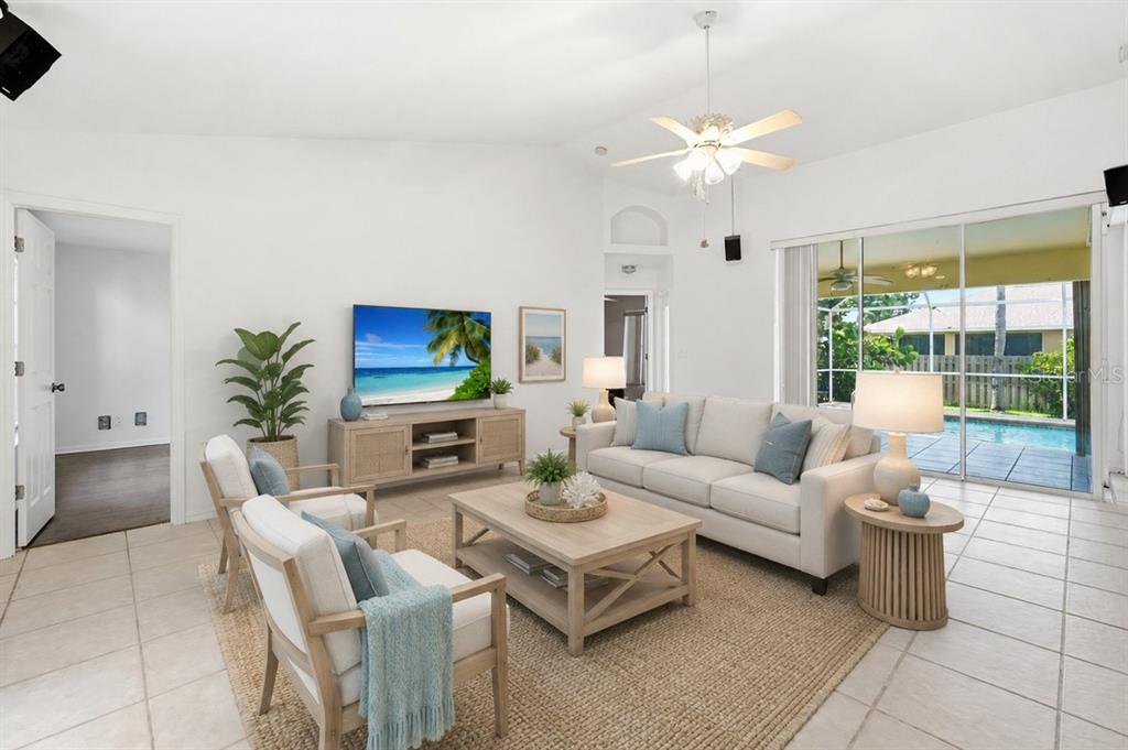 A bright living room features a white sofa, two armchairs, a coffee table, and a pool — 2408 SW 53RD STREET, CAPE CORAL, FL