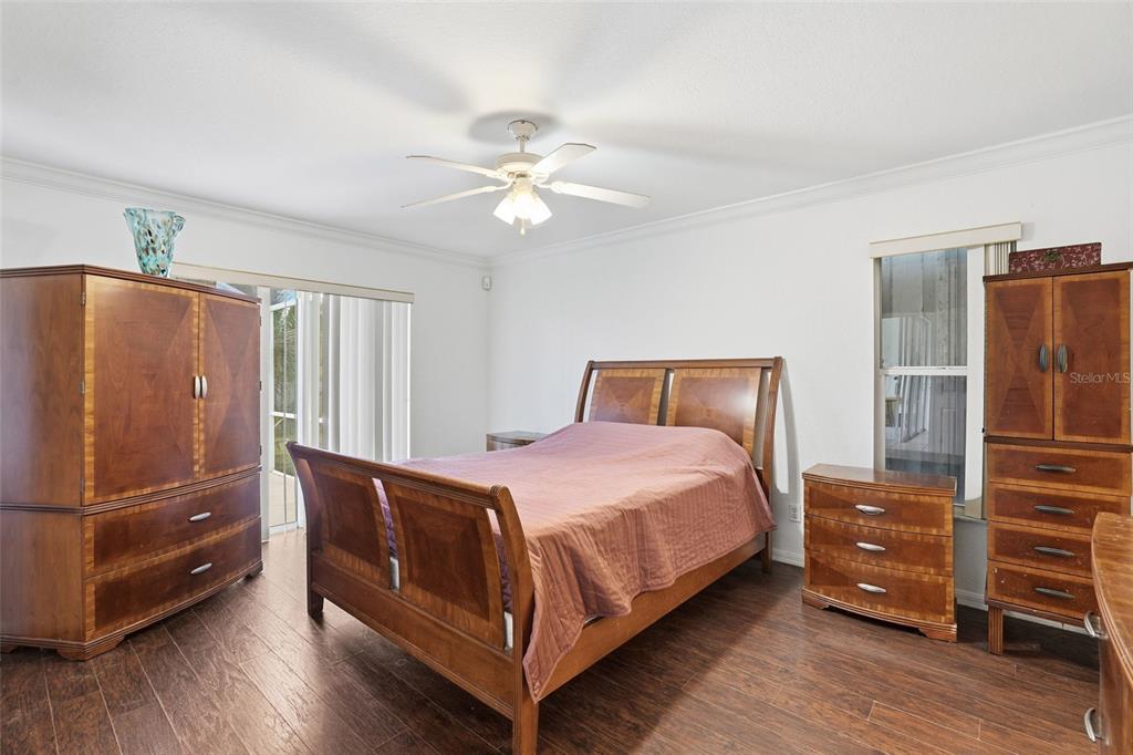 A bedroom with wood-look flooring, a wooden bed frame, matching furniture, and a ceiling fan — 2408 SW 53RD STREET, CAPE CORAL, FL