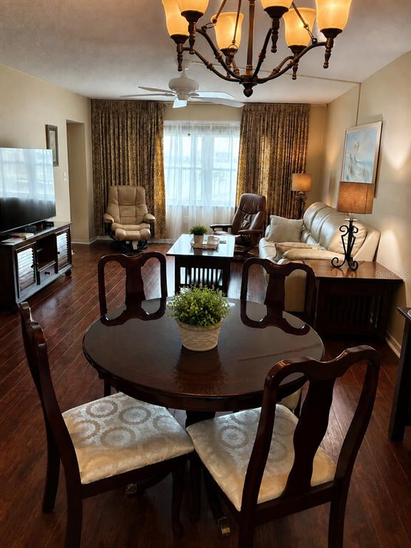 A dining area with a round table and chairs opens into a living room — 4575 COVE CIRCLE UNIT 506, ST PETERSBURG, FL
