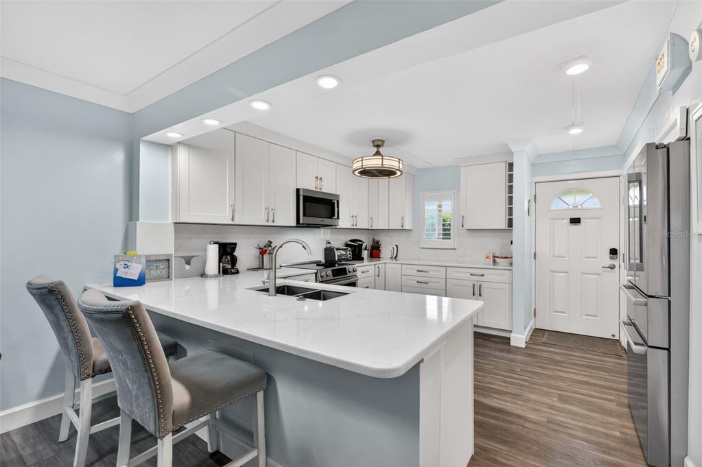 A modern kitchen features white cabinets, quartz countertops, a breakfast bar, and stainless steel appliances — 4 OCEAN TRACE ROAD UNIT 104, ST AUGUSTINE, FL