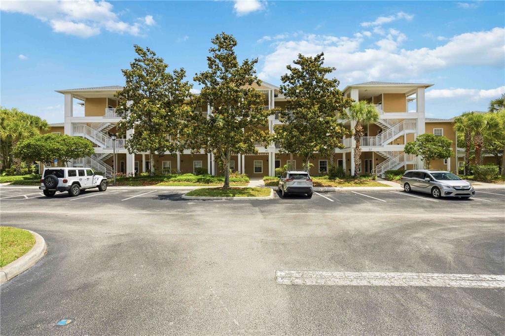A three-story apartment building with exterior staircases and a parking lot in the foreground — 114 RUM RUN, DAVENPORT, FL