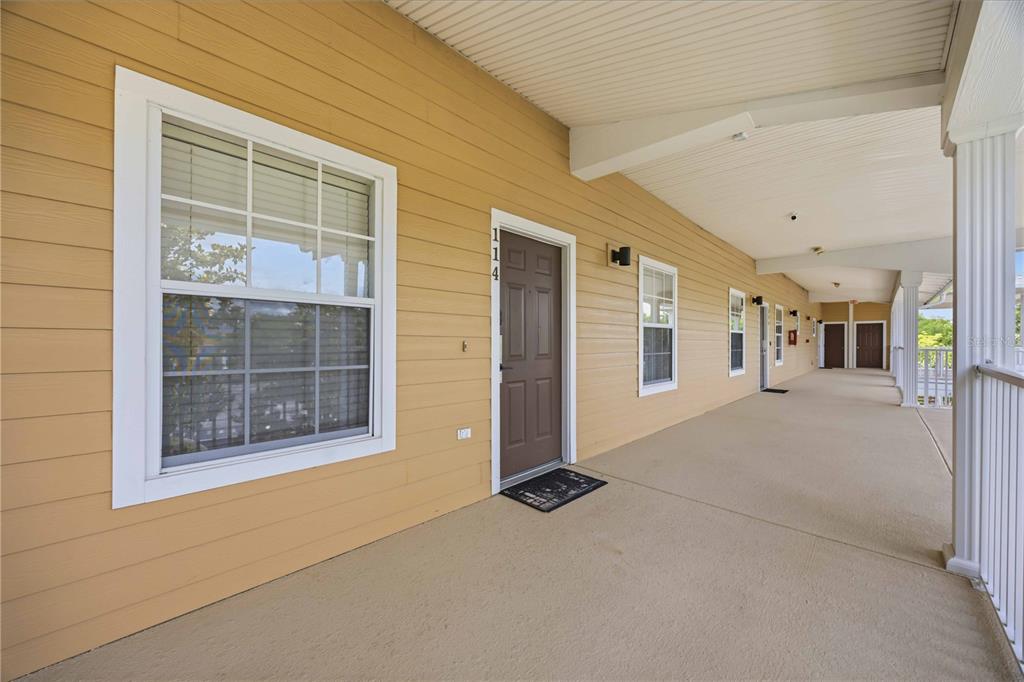 A covered exterior walkway features tan siding, multiple brown doors, and white-framed windows — 114 RUM RUN, DAVENPORT, FL