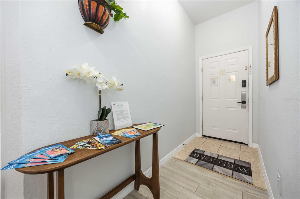 An entryway features a wooden console table, a white door, and a welcome mat — 114 RUM RUN, DAVENPORT, FL