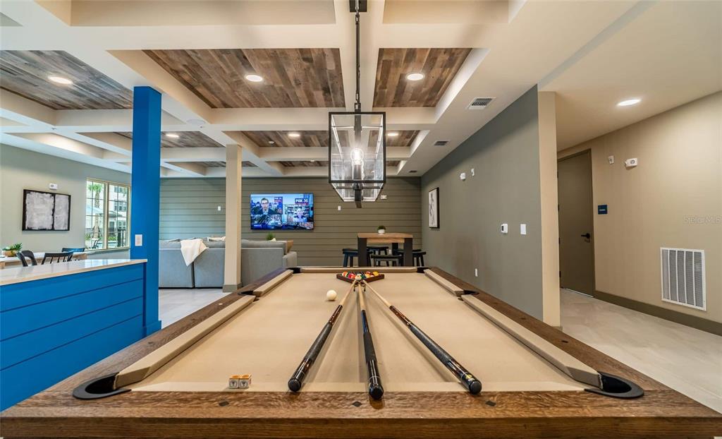 A game room features a pool table, wood-paneled ceiling, and a television mounted on a wall — 6629 DAN DICIOLLA DRIVE UNIT A4, WILDWOOD, FL