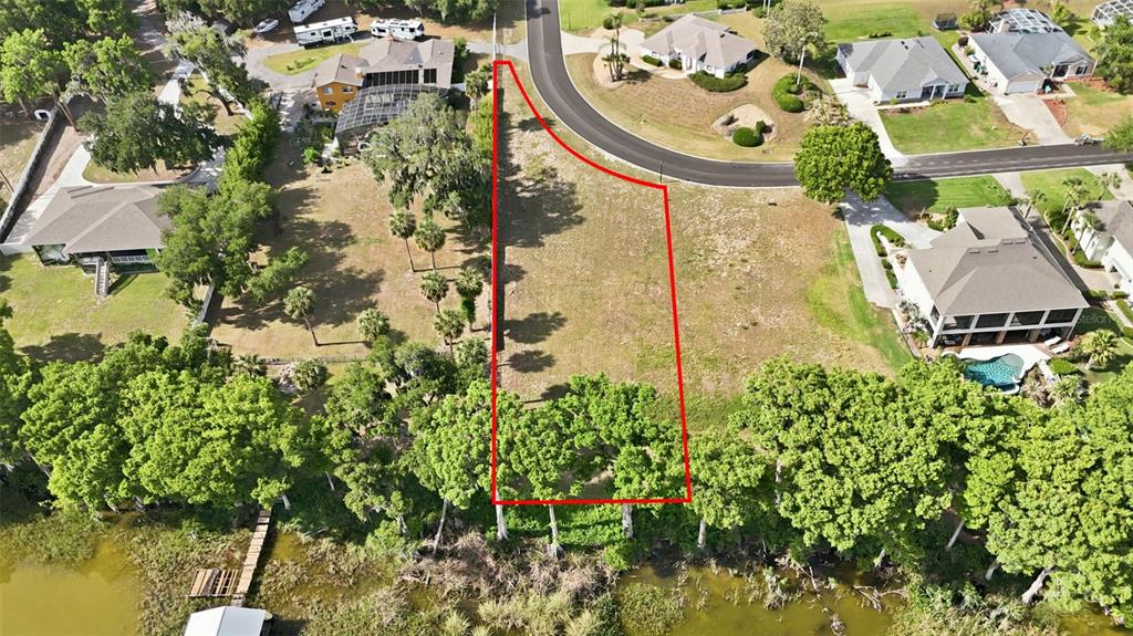 An aerial view shows a vacant, rectangular residential lot outlined in red bordering a lake — INDIAN TRAIL, EUSTIS, FL