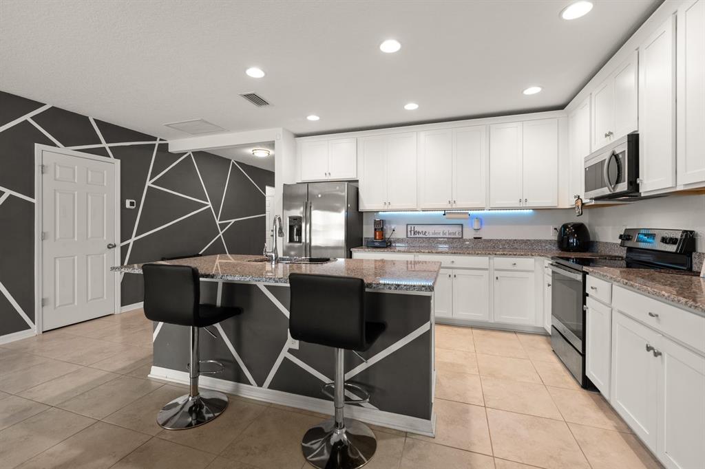 A kitchen with white cabinets, granite countertops, stainless steel appliances, and a central island — 13120 CONQUISTADOR LOOP, SPRING HILL, FL