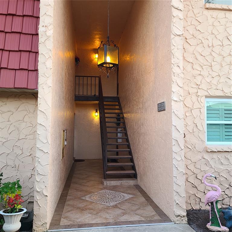 An outdoor staircase leads to an upper landing between two textured, light-colored building walls — 220 BUTTONWOOD CIRCLE UNIT 220, SEMINOLE, FL