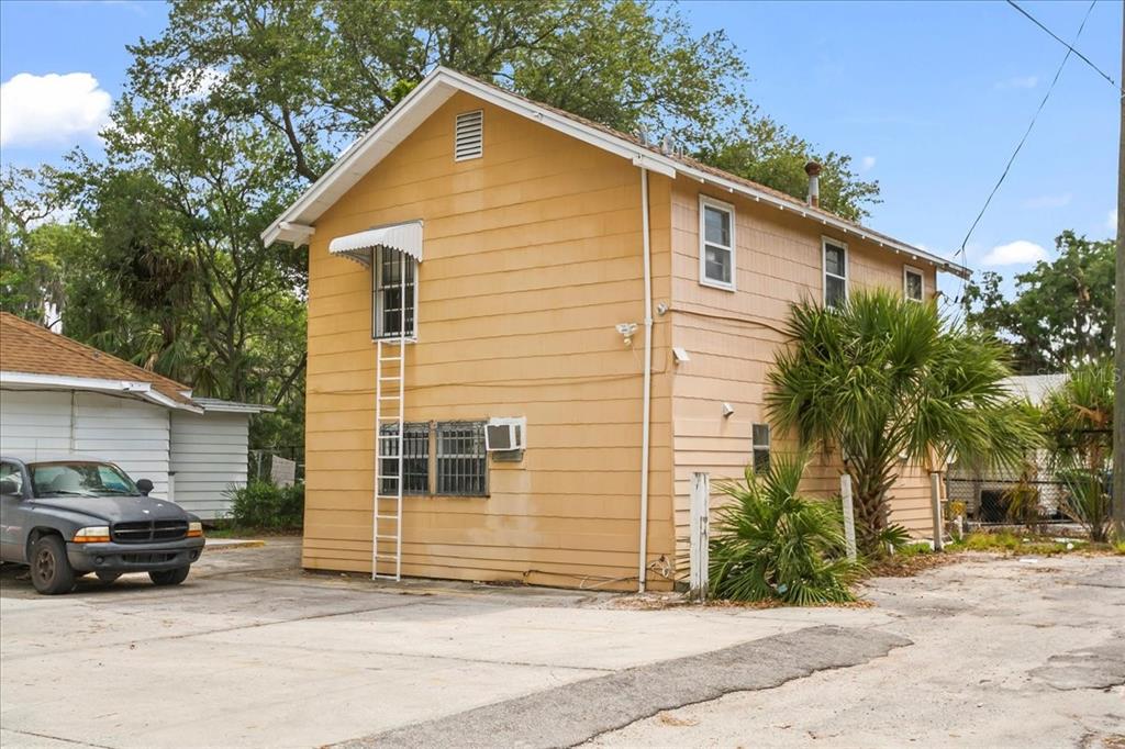 A two-story yellow house with a metal ladder leading to an upper-level window — 724 W CENTRAL AVENUE, WINTER HAVEN, FL