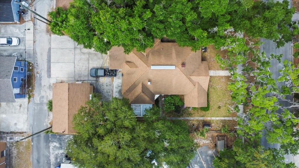 An aerial view shows a house with a brown roof, surrounding trees, and paved parking — 724 W CENTRAL AVENUE, WINTER HAVEN, FL