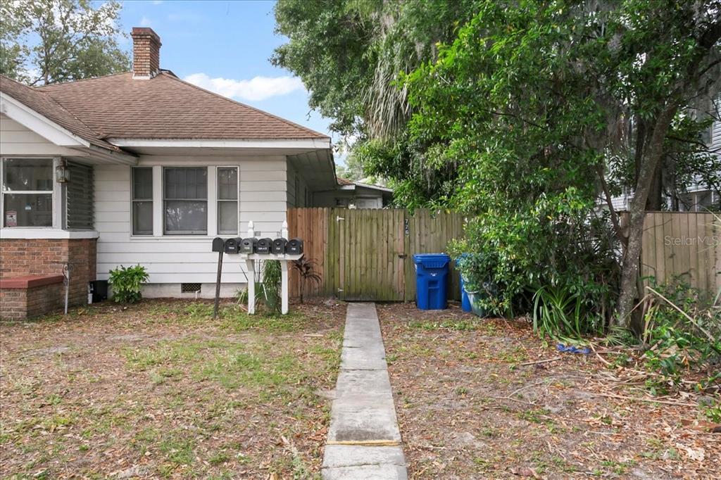 A white house exterior features a wooden fence, a concrete walkway, and a row of mailboxes — 724 W CENTRAL AVENUE, WINTER HAVEN, FL
