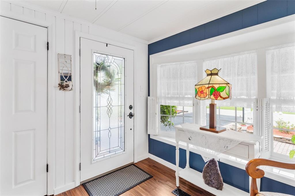 An entryway features a white front door, wood-look flooring, and blue walls with windows — 2470 KAREN DRIVE, MOUNT DORA, FL